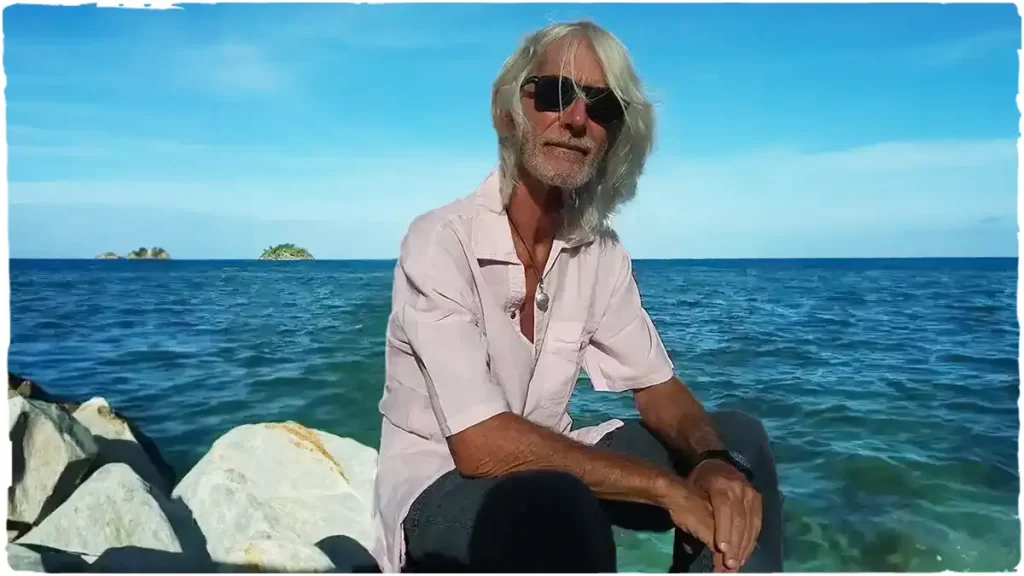 mode bohème Homme assis sur la jetée au bord de la mer portant une chemise blanche